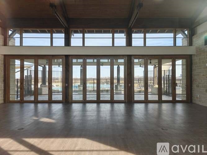 A spacious room with large windows and wooden floors.