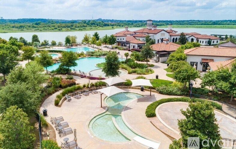 A large outdoor swimming pool surrounded by trees and a building in the background.
