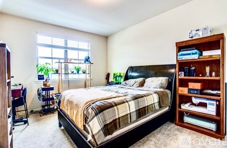 A bedroom with a large bed and a wooden bookshelf.
