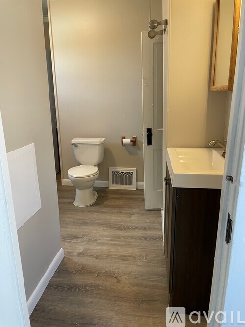 A bathroom with a toilet, sink, and mirror.