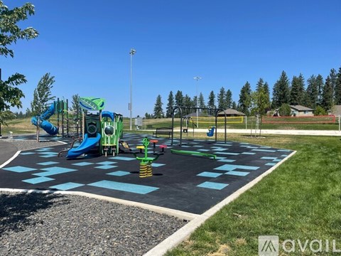 A playground with a blue and green slide and a checkerboard pattern on the ground.