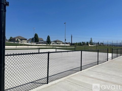 A black fence runs along a sidewalk in front of a grassy area.