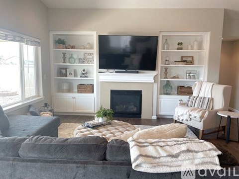 A living room with a grey couch, a white chair, and a fireplace.