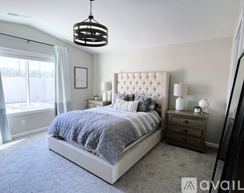 A bedroom with a large bed, a nightstand, and a window with curtains.
