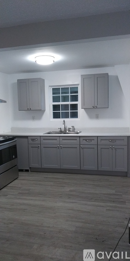 A kitchen with grey cabinets and a window.
