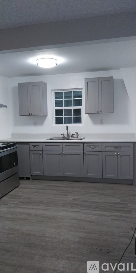 A kitchen with grey cabinets and a window.