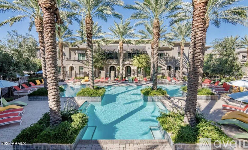 A pool surrounded by palm trees and lounge chairs.