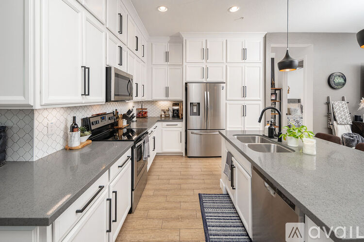 A kitchen with white cabinets and a grey counter top.