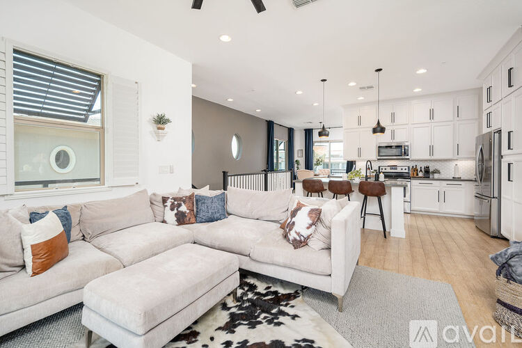 A modern living room with a white sofa and a kitchen in the background.