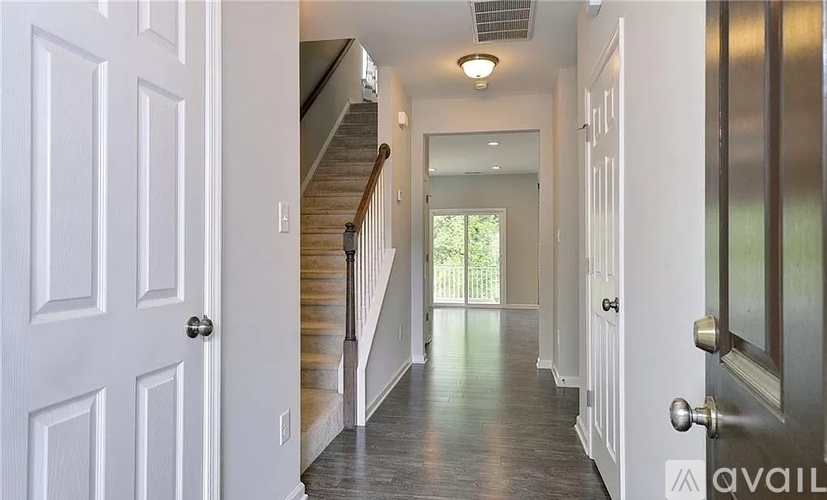 A hallway with white doors and a wooden staircase.