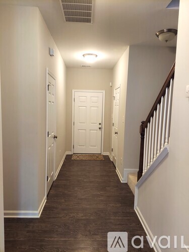 A hallway with a white door and a staircase on the right.