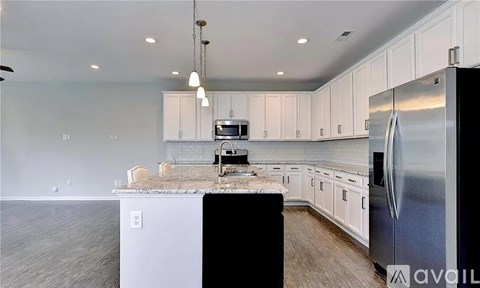 A kitchen with white cabinets and a black island.