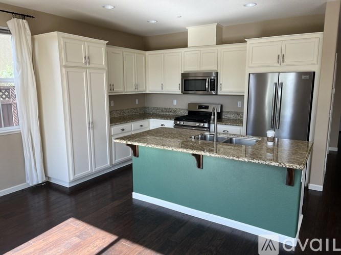 A kitchen with a green island and white cabinets.