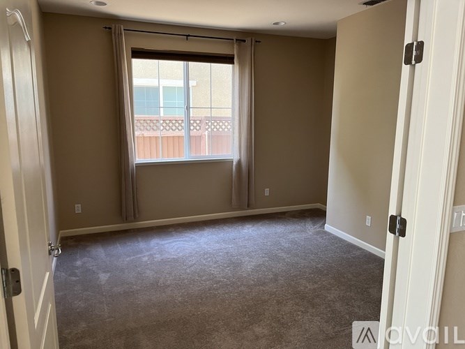 A room with a carpeted floor and a sliding glass door leading to a balcony.