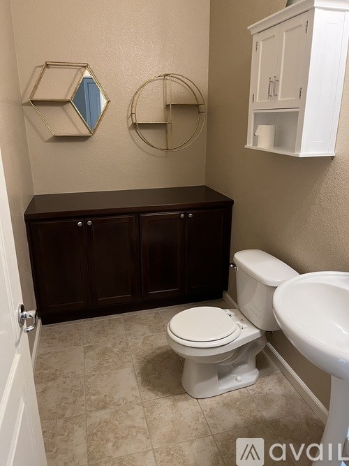 A bathroom with a toilet, sink, and a mirror.