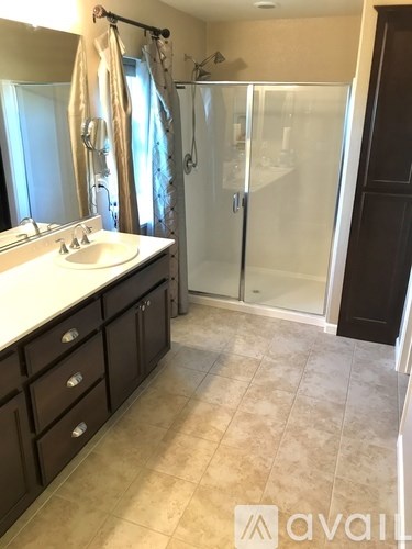 A bathroom with a sink, mirror, and shower.