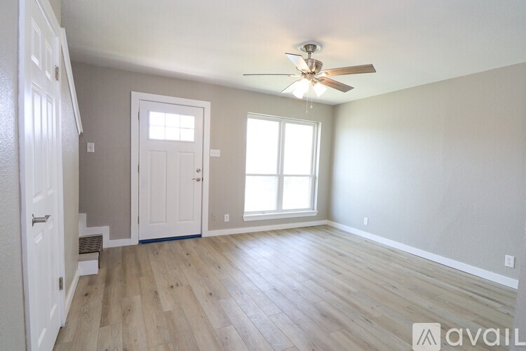 A room with a ceiling fan and wooden flooring.