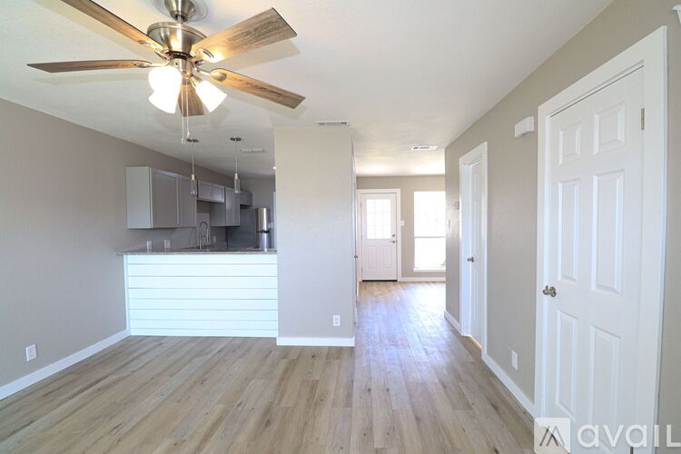 A spacious room with a ceiling fan and wooden flooring.