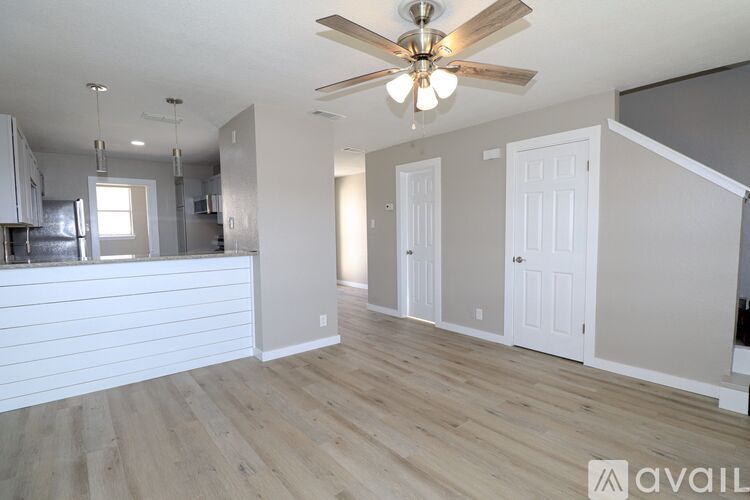 A spacious living room with a ceiling fan and hardwood floors.