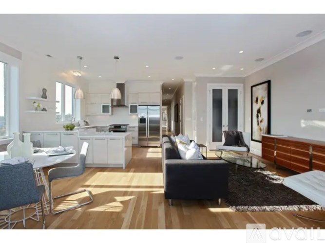 A modern living room with a kitchen area in the background.