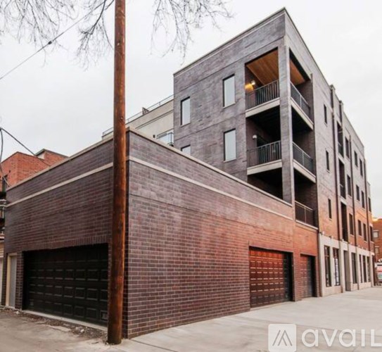 A modern multi-story building with a brick facade and a balcony on the top floor.