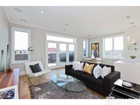 A modern living room with a black couch and a glass coffee table.