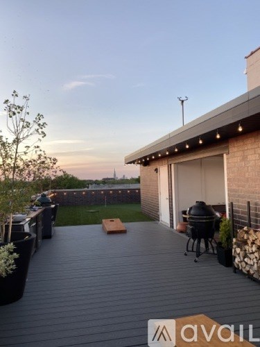 A patio with a grill and chairs is set up on a deck.