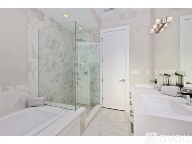 A bathroom with a marble patterned shower and a white bathtub.