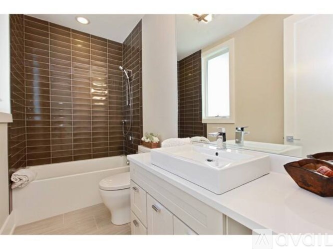 A white bathroom with a toilet, sink, and a window with blinds.