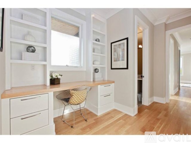 A kitchen with white cabinets and a wooden floor.