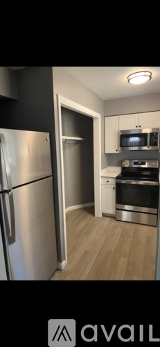 A kitchen with a stainless steel refrigerator and wooden flooring.