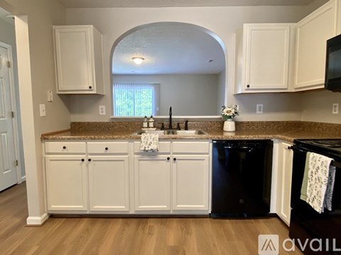 A kitchen with white cabinets and a black dishwasher.