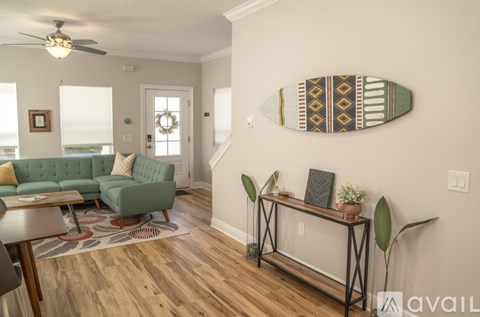 A living room with a green couch and a surfboard picture on the wall.