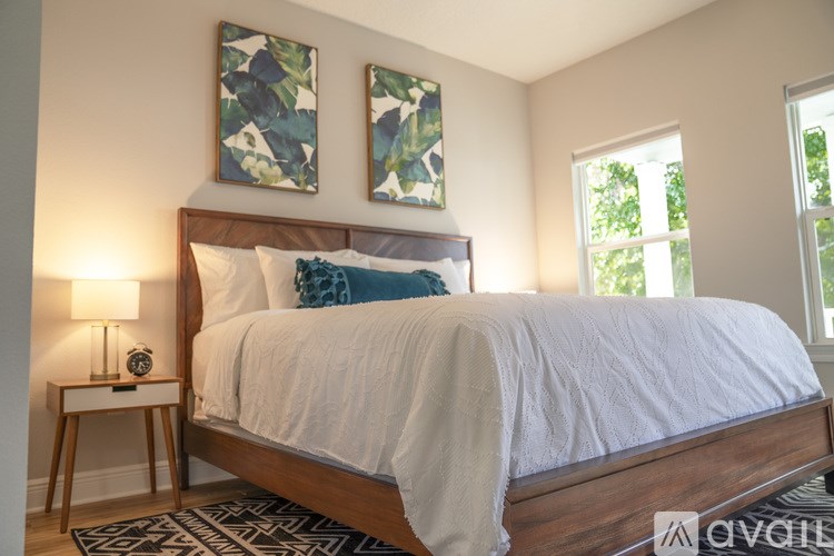A bedroom with a large bed and two abstract paintings on the wall.