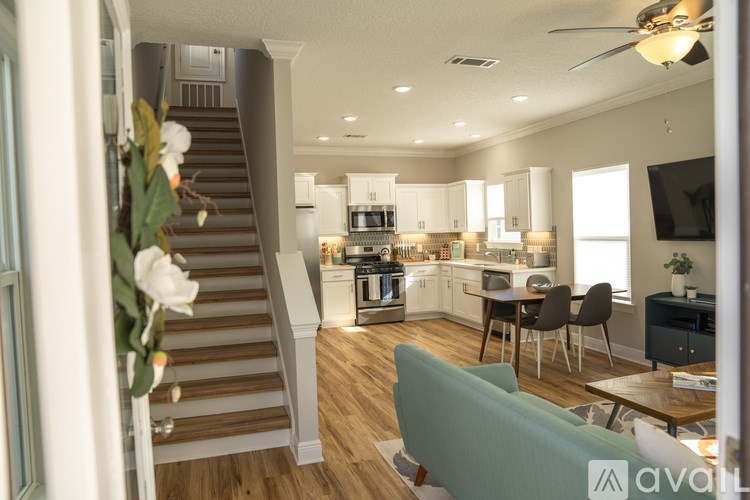 A living room with a staircase and a kitchen in the background.