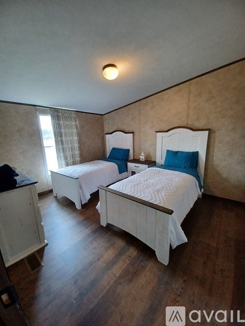 Two twin beds in a room with wooden floors and beige walls.