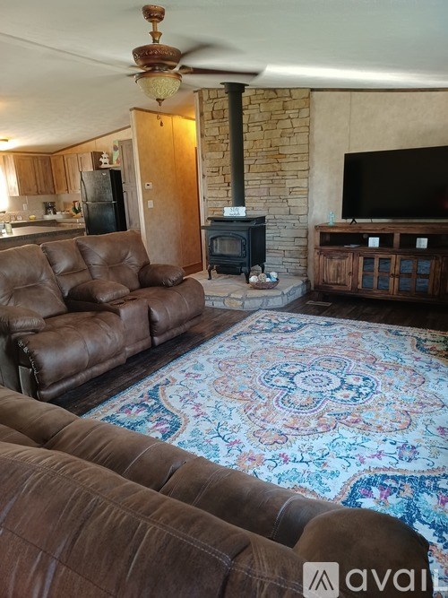 A living room with a brown leather couch and a patterned rug.