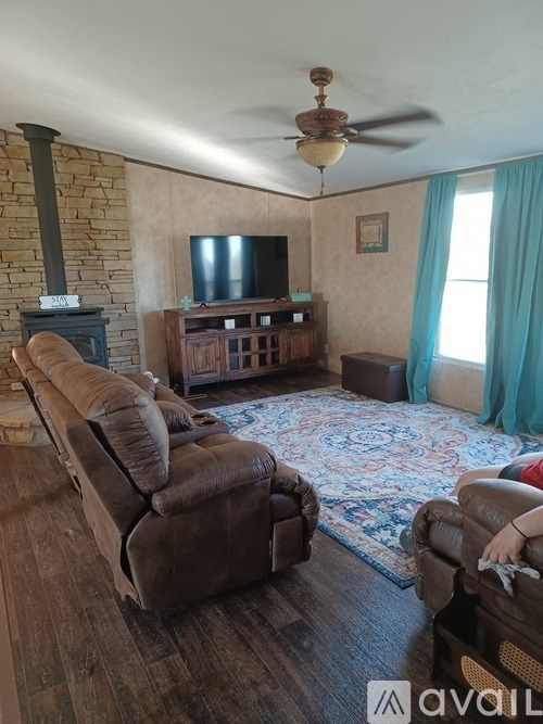 A living room with a brown leather couch and a television on a wooden stand.