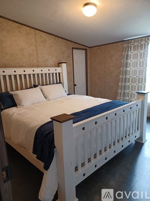 A bedroom with a white bed and a blue blanket.