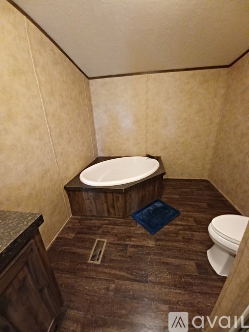 A bathroom with a wooden floor and a white toilet.