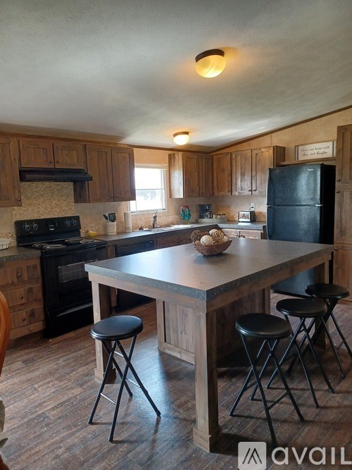 A kitchen with a black fridge and wooden cabinets.