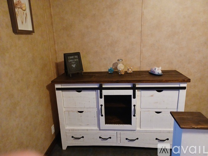 A kitchen island with a wooden top and drawers is in front of a beige wall.