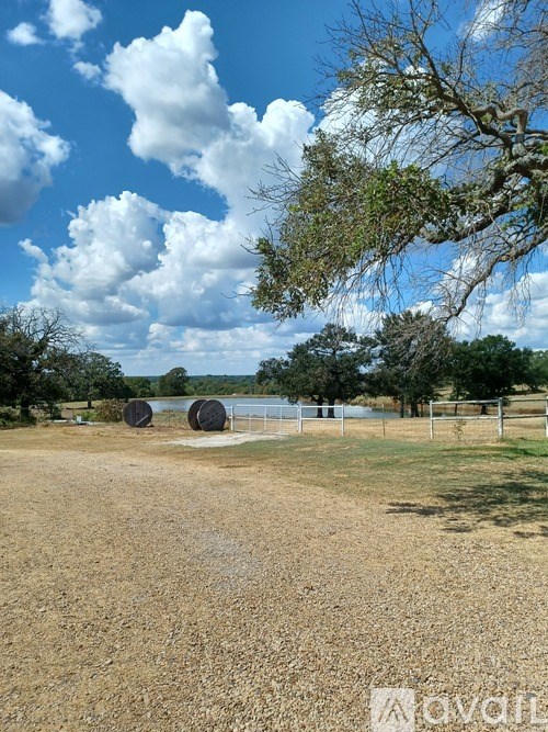A field with a fence and trees in the distance.