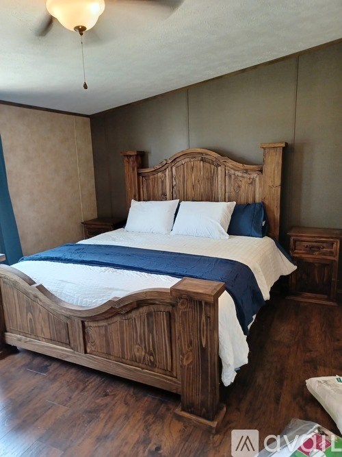 A bed with a wooden headboard and footboard with a white comforter and a blue blanket.