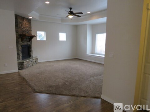 A living room with a stone fireplace and a rug on the floor.