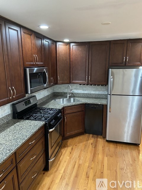 A kitchen with wooden cabinets and a stainless steel refrigerator.
