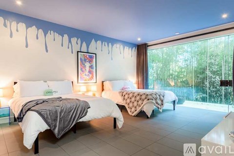 A bedroom with two beds and a painting on the wall.