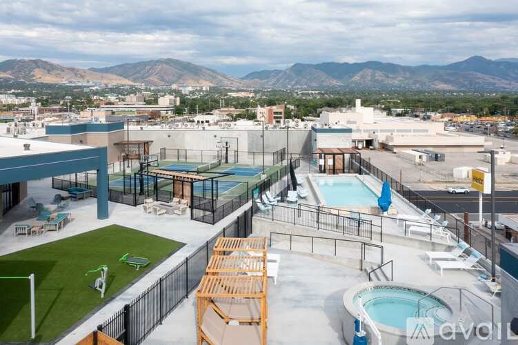 A rooftop pool area with a soccer field and mountains in the background.