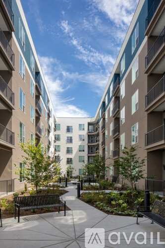A sunny day at a modern apartment complex with a walkway and benches.
