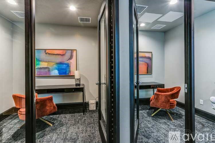 A room with a painting on the wall and two chairs.